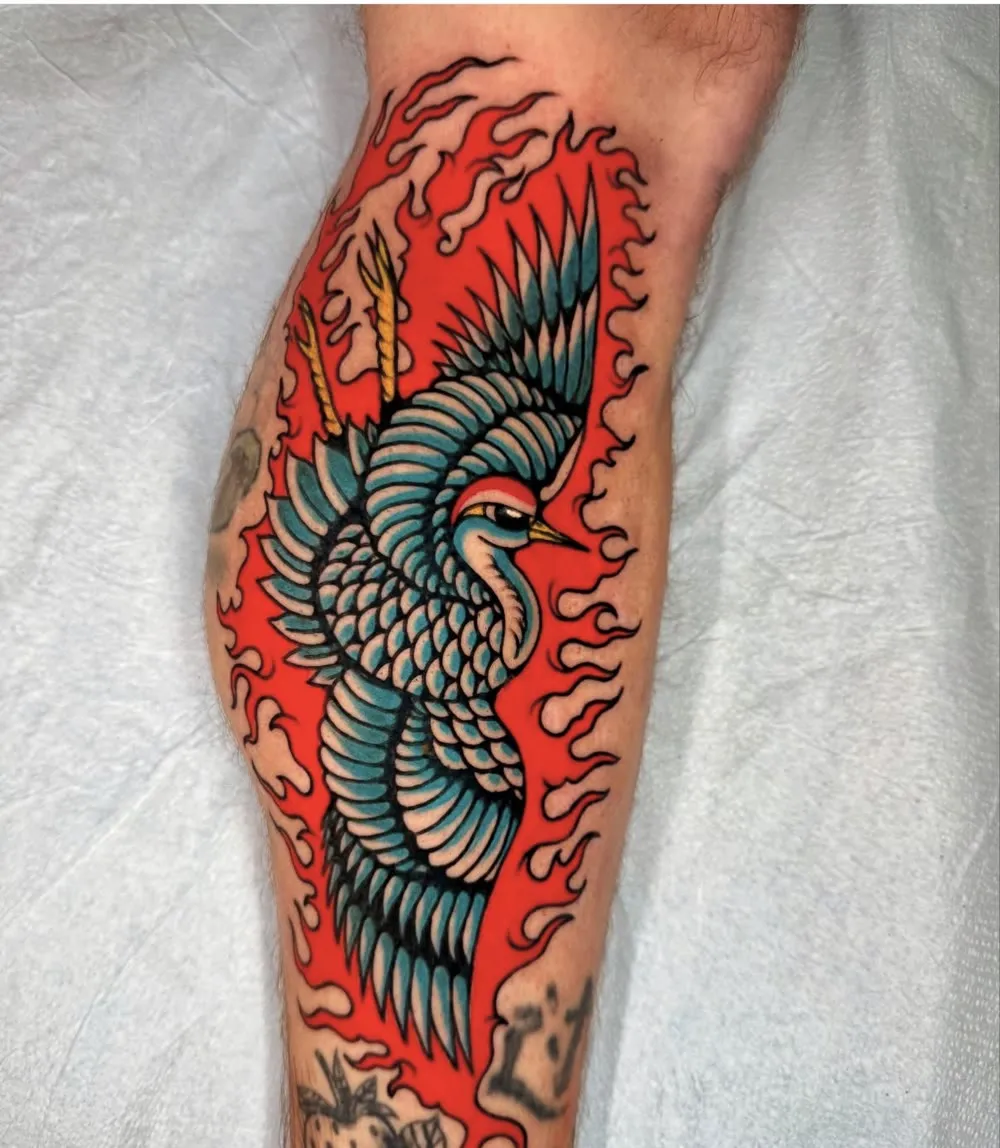 Crane in red flames, color traditional tattoo on a calf