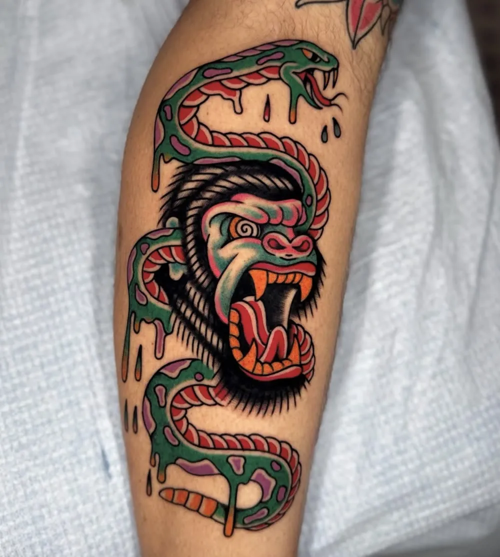 Gorilla with spiral eyes wrapped in a dripping green snake, color traditional tattoo on a calf